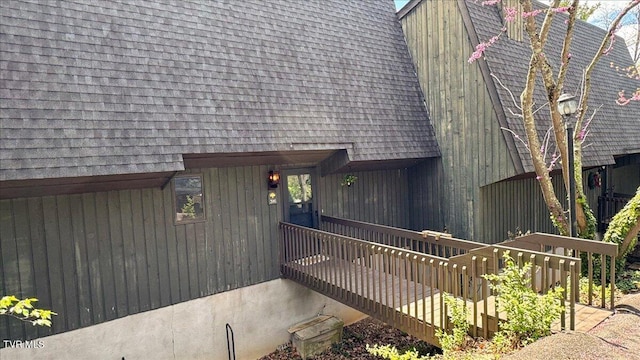 view of exterior entry with roof with shingles