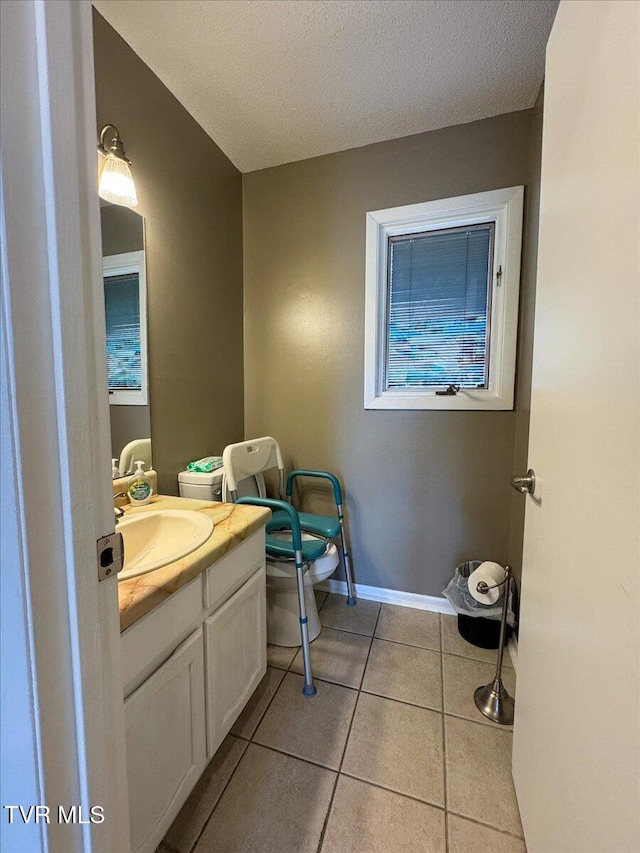 half bathroom with tile patterned flooring, vanity, a textured ceiling, and baseboards