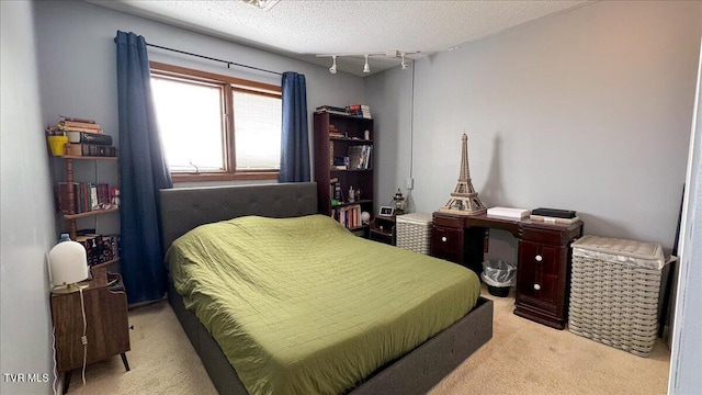 bedroom featuring a textured ceiling, rail lighting, and carpet floors