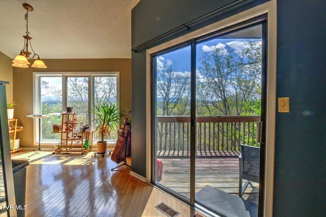 doorway with hardwood / wood-style floors, baseboards, visible vents, and a textured ceiling