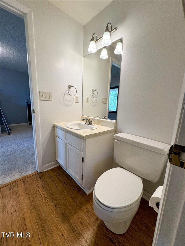 bathroom featuring toilet, wood finished floors, vanity, and baseboards