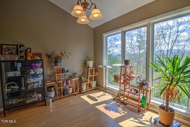sitting room featuring a wealth of natural light, wood finished floors, a chandelier, and vaulted ceiling
