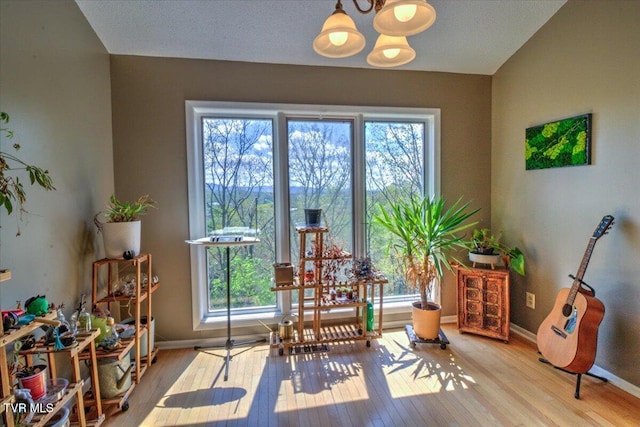 living area featuring wood finished floors, an inviting chandelier, and baseboards