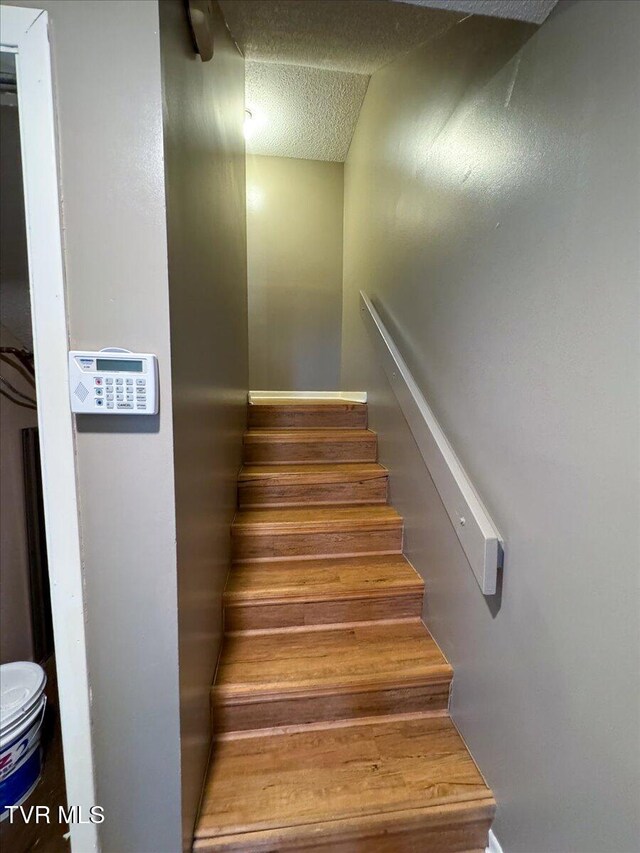 stairway featuring a textured ceiling and wood finished floors