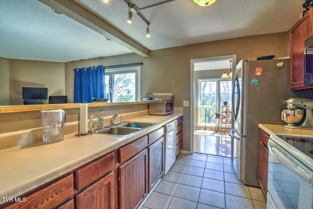 kitchen featuring white appliances, light tile patterned floors, light countertops, a textured ceiling, and a sink