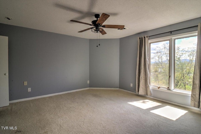 carpeted spare room with a textured ceiling, ceiling fan, baseboards, and plenty of natural light