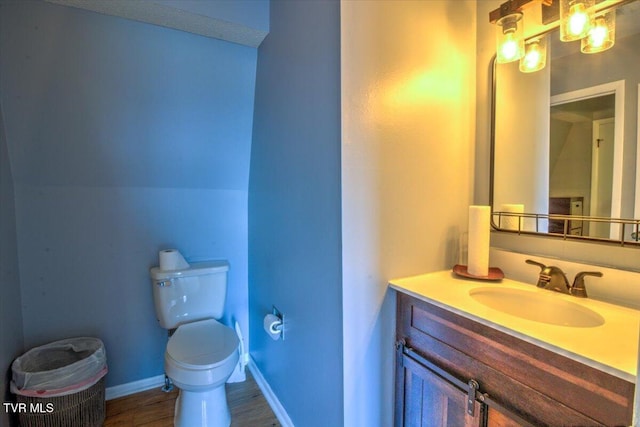 bathroom featuring toilet, wood finished floors, vanity, and baseboards
