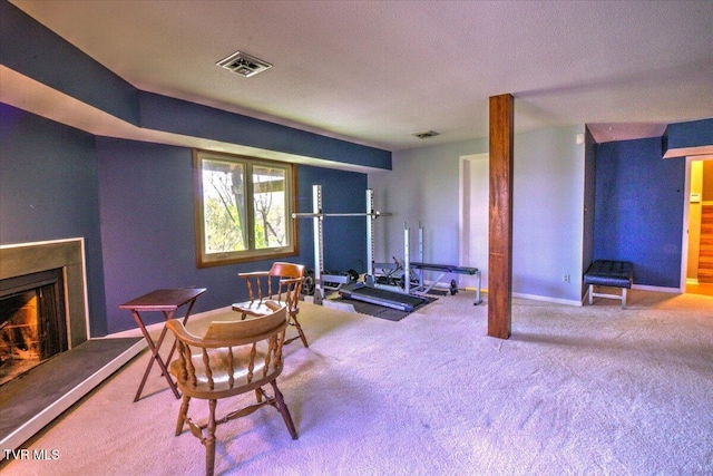 interior space with visible vents, baseboards, a warm lit fireplace, and carpet floors