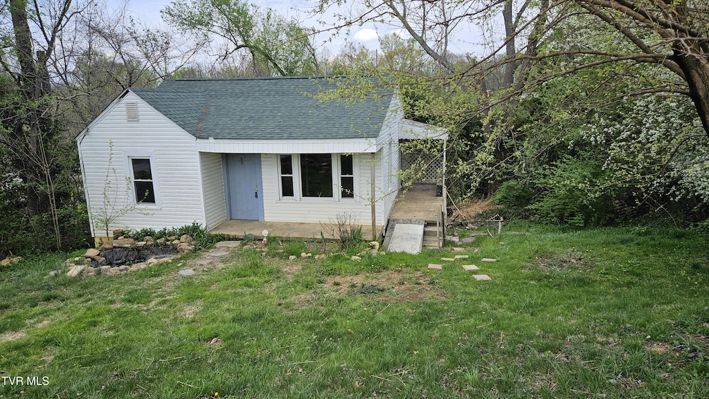 view of front of home featuring a front yard and roof with shingles