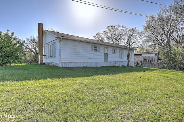 back of house with a chimney and a lawn