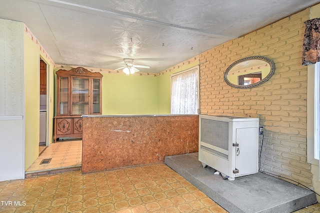 interior space featuring visible vents, a ceiling fan, a textured ceiling, a wainscoted wall, and light floors