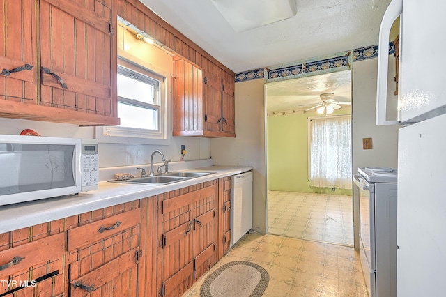 kitchen featuring a sink, light countertops, white appliances, a healthy amount of sunlight, and light floors