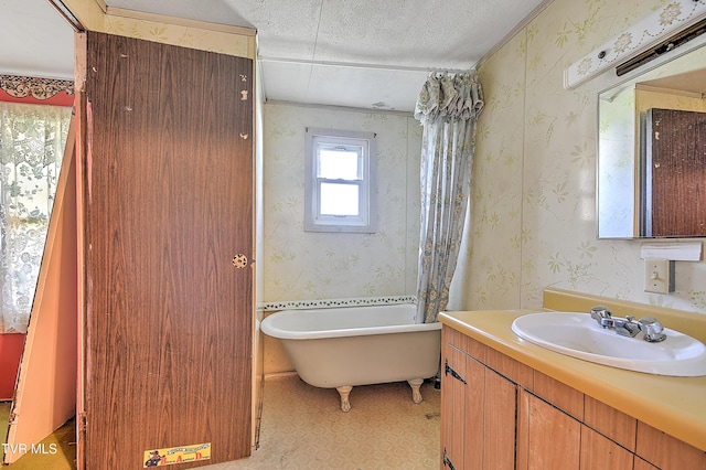 full bathroom with vanity, a textured ceiling, a soaking tub, and wallpapered walls