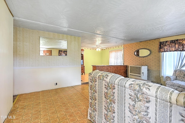 bedroom featuring a wainscoted wall, a textured ceiling, and wallpapered walls