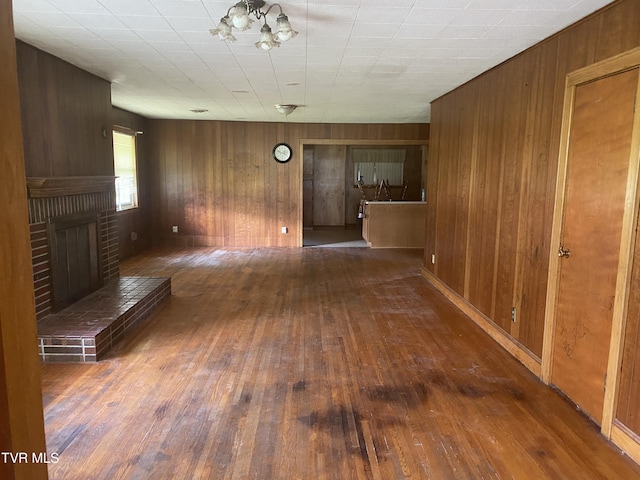6192 Hurricane Rd, Wise, VA 24293 - unfurnished living room featuring wood-type flooring, wooden walls, a fireplace, and a chandelier