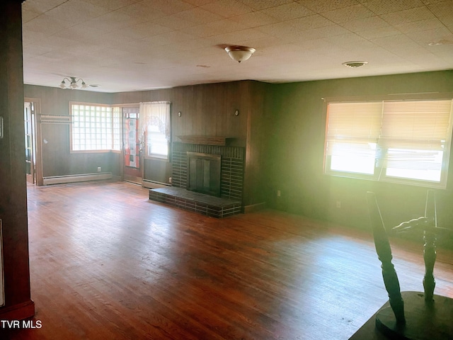 6192 Hurricane Rd, Wise, VA 24293 - unfurnished living room featuring a baseboard heating unit, wood finished floors, a fireplace, and wood walls