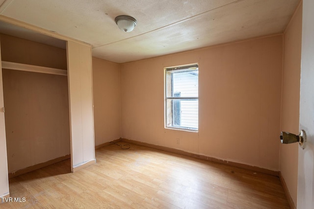 unfurnished bedroom featuring light wood-style flooring, a closet, and baseboards