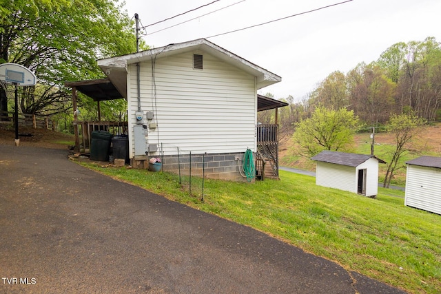 view of side of property with an outbuilding, a storage unit, and a yard