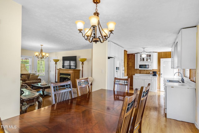 dining room featuring light wood-style flooring, a chandelier, a fireplace, and a textured ceiling