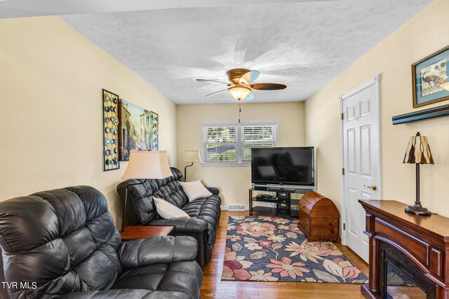living area featuring a textured ceiling, wood finished floors, and a ceiling fan