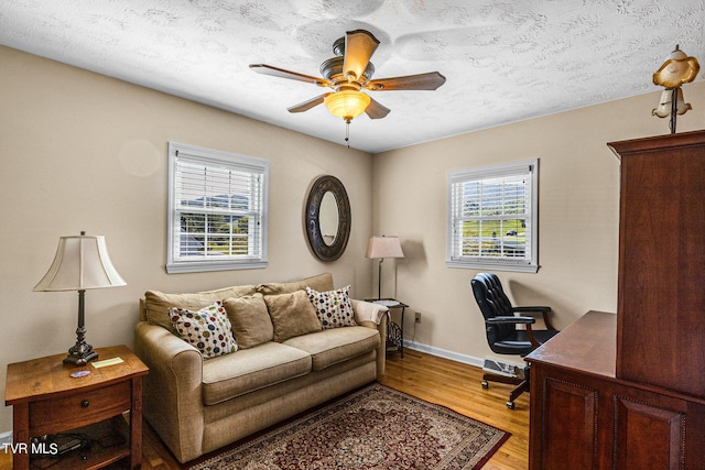office area with light wood-style flooring, baseboards, a ceiling fan, and a healthy amount of sunlight