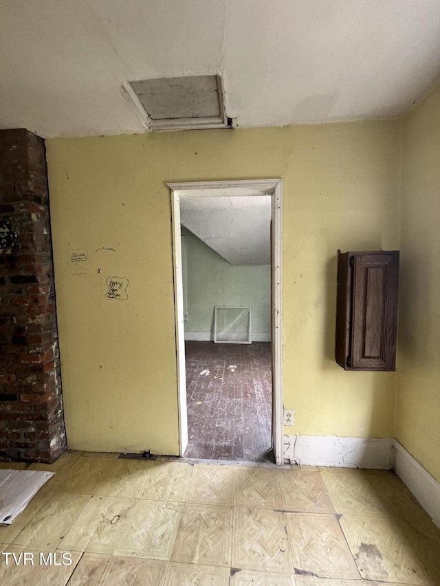 unfurnished room featuring attic access