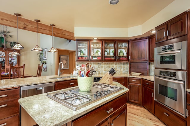 kitchen with light stone countertops, a center island, a sink, stainless steel appliances, and backsplash