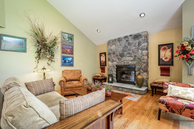 living room with a stone fireplace, light wood finished floors, and lofted ceiling