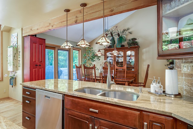 kitchen featuring light stone counters, dishwasher, a sink, lofted ceiling, and decorative light fixtures