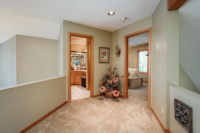 hall with a textured ceiling, carpet flooring, and baseboards