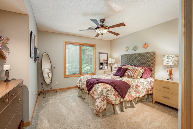 bedroom with ceiling fan, light colored carpet, baseboards, and a textured ceiling