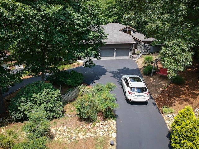 view of front of house featuring aphalt driveway, a shingled roof, stone siding, and an attached garage