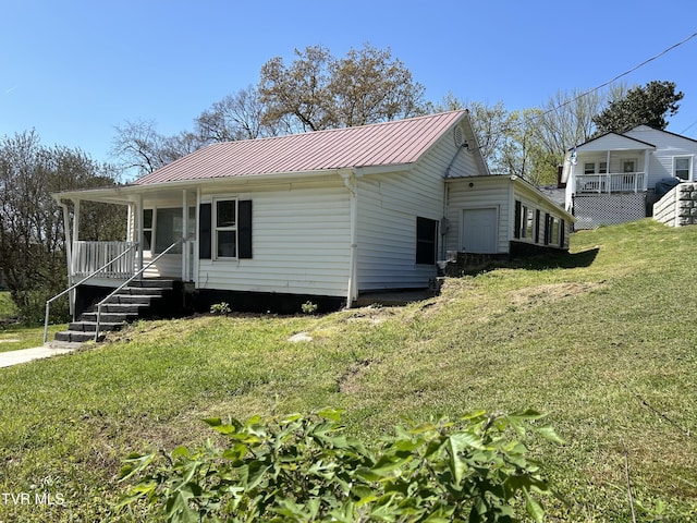 view of front of house featuring a standing seam roof, a front yard, metal roof, and covered porch