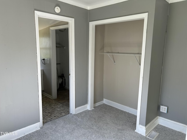 unfurnished bedroom featuring a closet, ornamental molding, visible vents, carpet flooring, and baseboards
