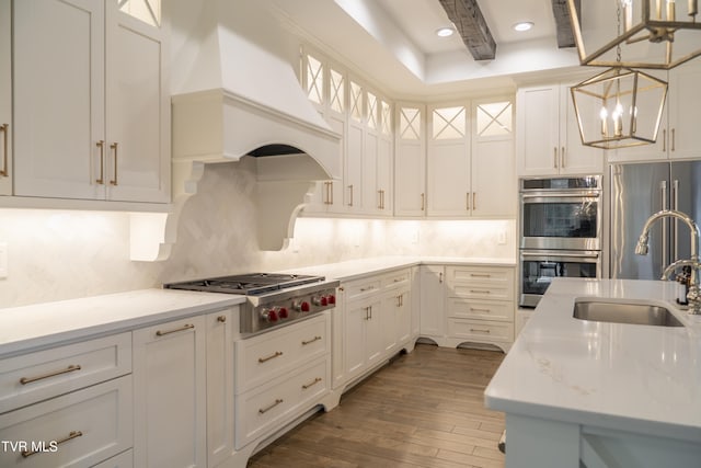 kitchen featuring custom exhaust hood, tasteful backsplash, an inviting chandelier, a sink, and stainless steel appliances