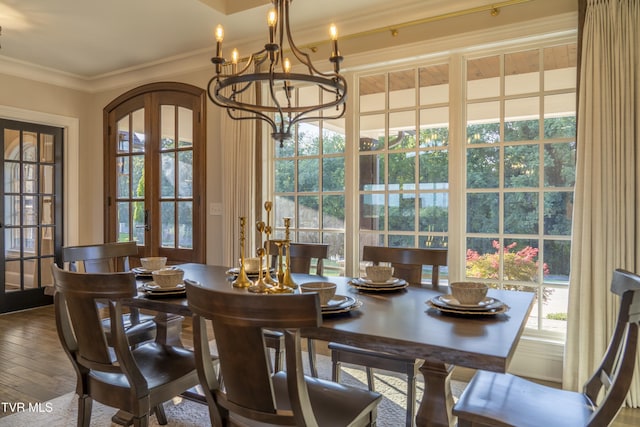 dining space with crown molding, french doors, wood-type flooring, and a chandelier
