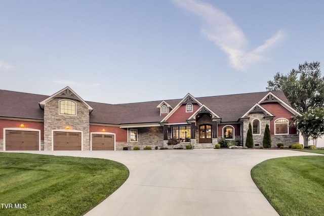 craftsman house with a front yard, an attached garage, stone siding, curved driveway, and roof with shingles