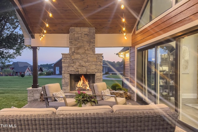patio terrace at dusk featuring a yard and an outdoor living space with a fireplace