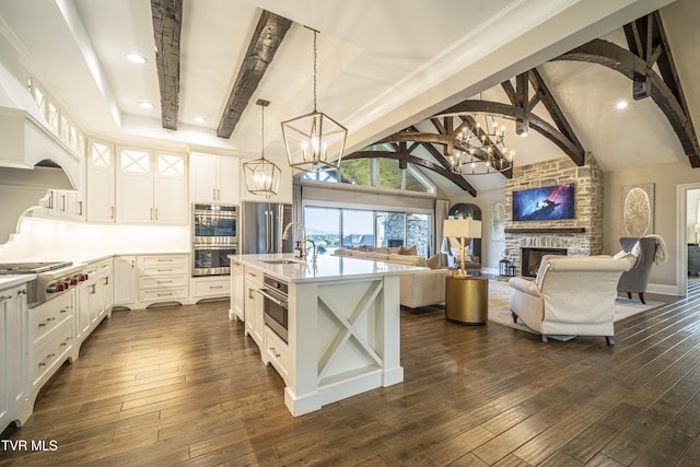 kitchen featuring a large fireplace, a chandelier, appliances with stainless steel finishes, a sink, and beam ceiling