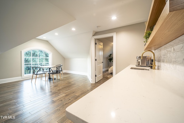 additional living space featuring dark wood-style flooring, baseboards, vaulted ceiling, recessed lighting, and a sink