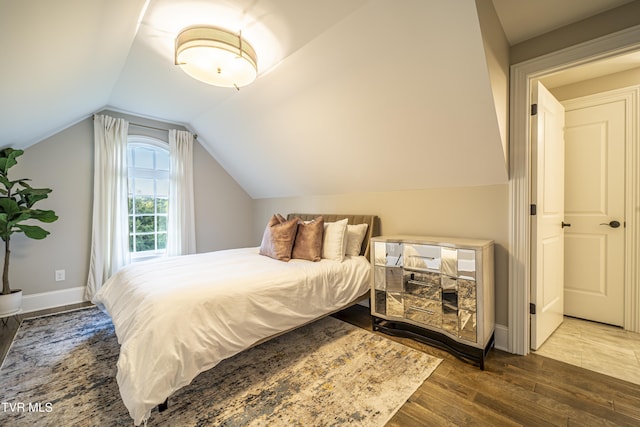 bedroom with baseboards, vaulted ceiling, and wood finished floors