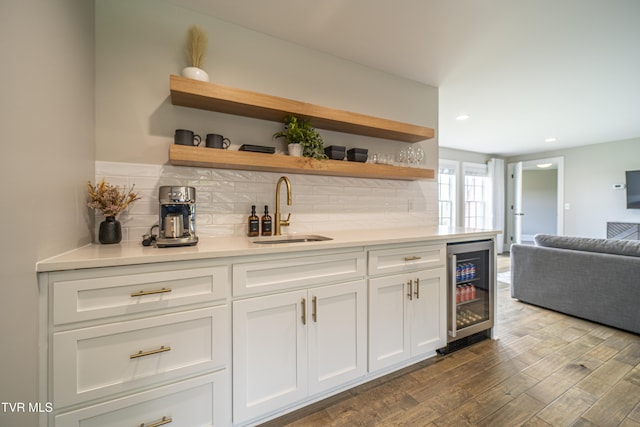 bar featuring a sink, dark wood-style flooring, wet bar, wine cooler, and decorative backsplash