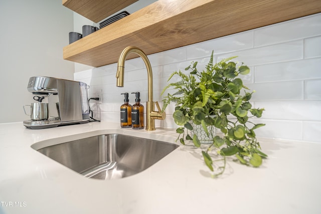 interior details with light countertops, decorative backsplash, a sink, and open shelves