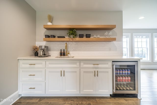 bar with backsplash, beverage cooler, a sink, and indoor bar
