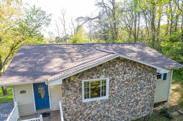 view of front of property featuring roof with shingles and stone siding