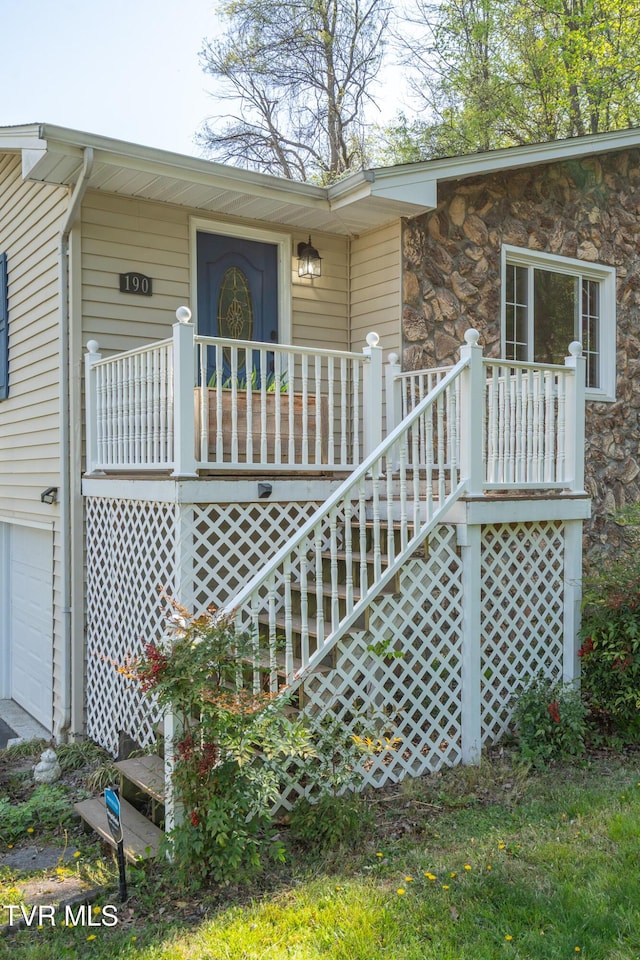 property entrance with a porch, an attached garage, and stone siding