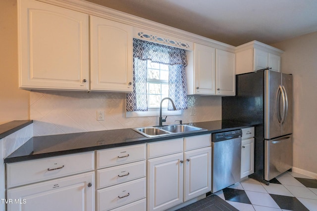 kitchen with tasteful backsplash, white cabinets, dark countertops, a sink, and stainless steel appliances