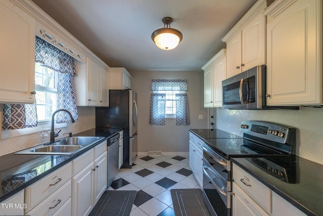 kitchen with appliances with stainless steel finishes, a sink, dark countertops, decorative backsplash, and baseboards