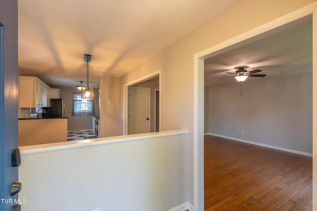 kitchen with freestanding refrigerator, white cabinets, decorative light fixtures, ceiling fan, and wood finished floors