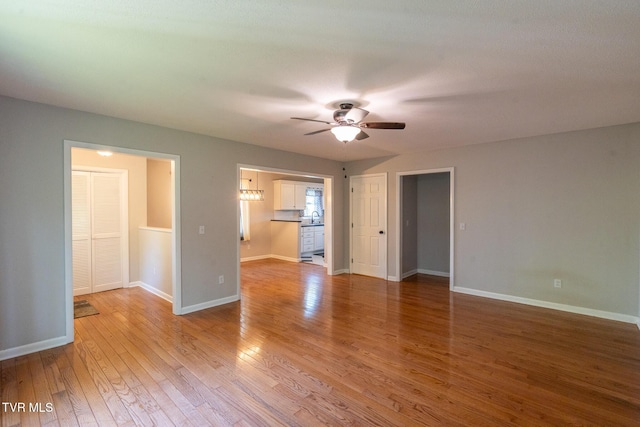 unfurnished room featuring light wood-style floors, ceiling fan, a sink, and baseboards